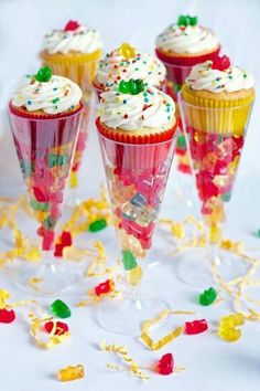 four cupcakes with white frosting and sprinkles on them sitting in small cones