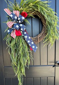 a wreath with an american flag bow hanging on the front door