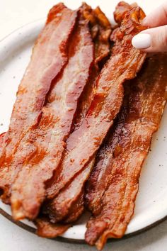 a person is holding bacon on a plate