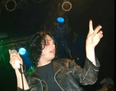 a young man is holding his hands up in the air while singing into a microphone