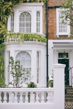 a white house with lots of windows and plants