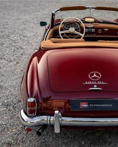 an old mercedes sports car is parked on the street with its hood up and steering wheel down