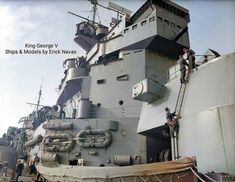 two men are standing on the side of a large ship while another man is working on it