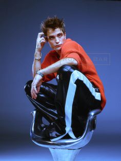 a young man sitting on top of a metal chair