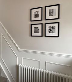 three black and white pictures hang on the wall above a radiator in a home