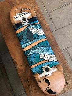 a skateboard is sitting on top of a wooden board with blue and white designs