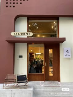 two chairs are sitting in front of the entrance to a coffee shop with people walking by