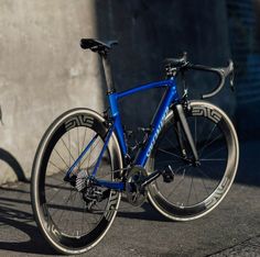 a blue bike parked next to a cement wall with a bicycle leaning up against it