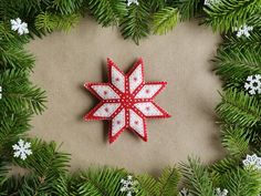 an ornament made out of red and white fabric sitting on top of evergreen branches