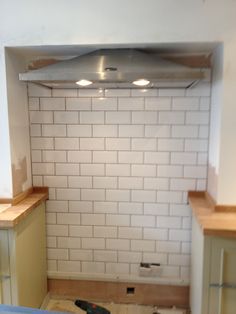 an empty kitchen with white brick walls and wood flooring in the middle of it