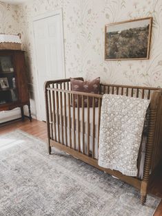 a baby's crib in the corner of a room with floral wallpaper