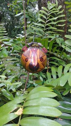 an animal ornament hanging from a tree in the forest with lots of leaves