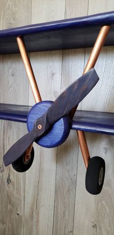 an airplane made out of wood and some metal parts hanging on the wall with wheels