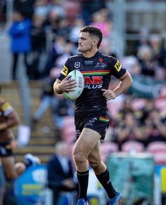 a rugby player is running with the ball in his hand as people watch from the stands