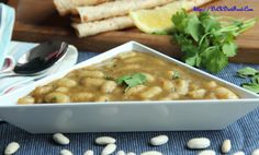 a white bowl filled with beans and cilantro on top of a blue cloth