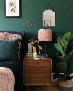 a bedroom with green walls and a pink lamp next to a wooden chest of drawers