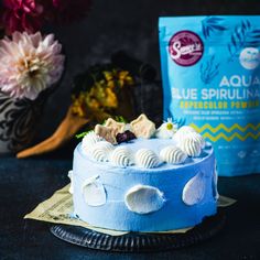 a blue cake sitting on top of a table next to a bag of flour and flowers