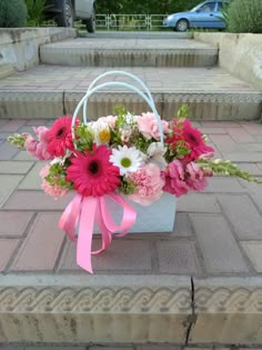 a bouquet of pink and white flowers sitting in a basket on the ground next to steps