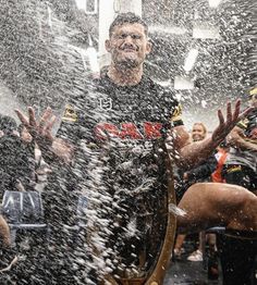 a man standing in front of a group of people with his hands out and water splashing all over him