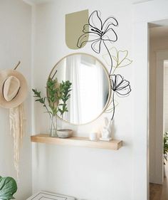 a mirror on the wall above a table with some plants in it and a hat