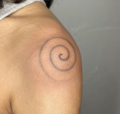 a woman's back with a tattoo on her left shoulder and an abstract swirl in the middle