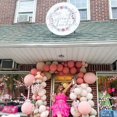 a woman standing in front of a store with balloons