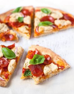 four pieces of pizza with tomatoes, cheese and basil on top sitting on a cutting board