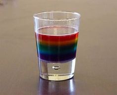 a rainbow colored liquid in a glass on a table