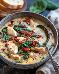 a bowl of chicken and spinach soup with bread on the side, ready to be eaten