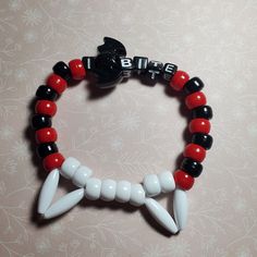 "Sink your teeth into style with our \"I Bite\" Vampire Kandi Single! This eye-catching piece comes complete with a bat charm, capturing the essence of nocturnal allure. Feeling more divine? Opt for crosses - just let us know!  The default colors are as shown, but for a personalized touch, message us to explore the array of customizable color options. Unleash your inner vampire with this uniquely crafted kandi creation!" Pulseras Kandi, Diy Kandi Bracelets, Diy Kandi, Kandi Kid, Vampire Fangs, Kandi Patterns, Wilbur Soot, Kandi Bracelets, Scene Kids