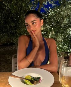 a woman sitting at a table with a plate of food in front of her