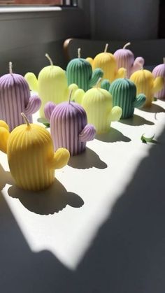 many different colored cupcakes are lined up on a white table with shadows from the window