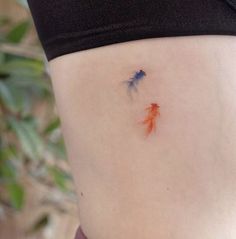 a woman's stomach with two goldfish tattoo on the side and one blue fish in the middle