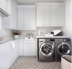 a washer and dryer in a white laundry room with cabinets on the wall