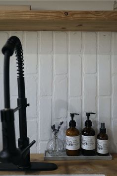 three soap dispensers sitting on top of a counter next to a faucet