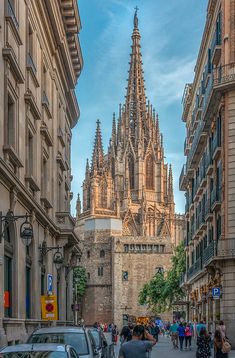 people are walking down the street in front of an old cathedral