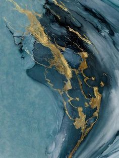 an abstract painting with gold and black paint on the water's surface, as seen from above