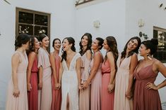 a group of women standing next to each other in front of a white building smiling