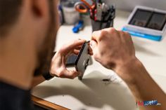 a man is holding a cell phone while sitting at a desk