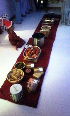 a long table filled with food on top of a white floor covered in red rugs