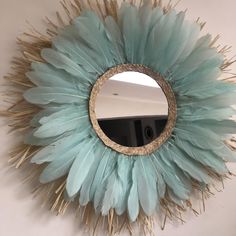 a mirror that is on the wall with some feathers in it and a light blue color