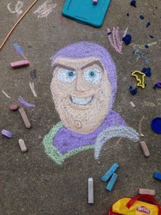 a child's drawing on the ground with crayons and other toys nearby