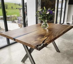 a wooden table with metal legs and a vase filled with flowers