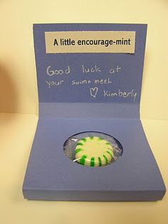 a green and white brooch sitting on top of a blue card board in a box