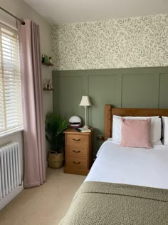 a bed sitting next to a window with pink pillows and blankets on top of it