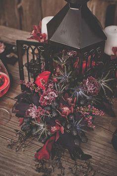 flowers and candles are sitting on a wooden table next to an old fashioned candle holder