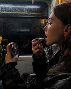 a woman sitting on a bus while holding a cell phone in her hand and looking at the screen