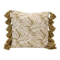 a beige and white pillow with tassels on the front, featuring palm leaves