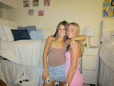 two young women standing next to each other in front of a bed with white sheets