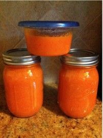 three jars filled with orange liquid sitting on top of a counter